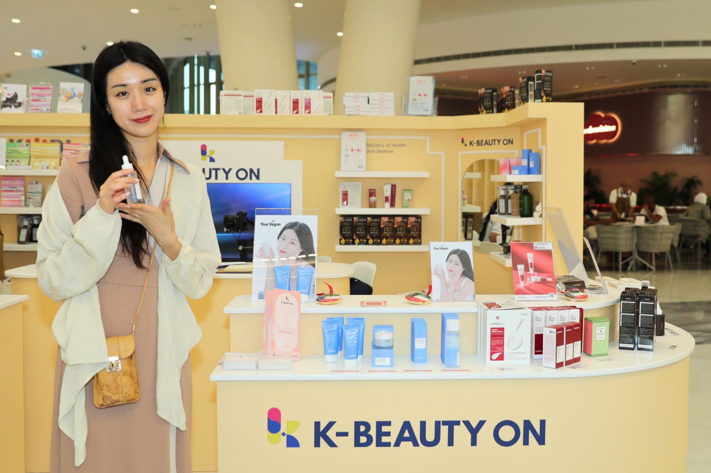 Korean woman smiling and holding sunscreen bottle by K-Beauty On